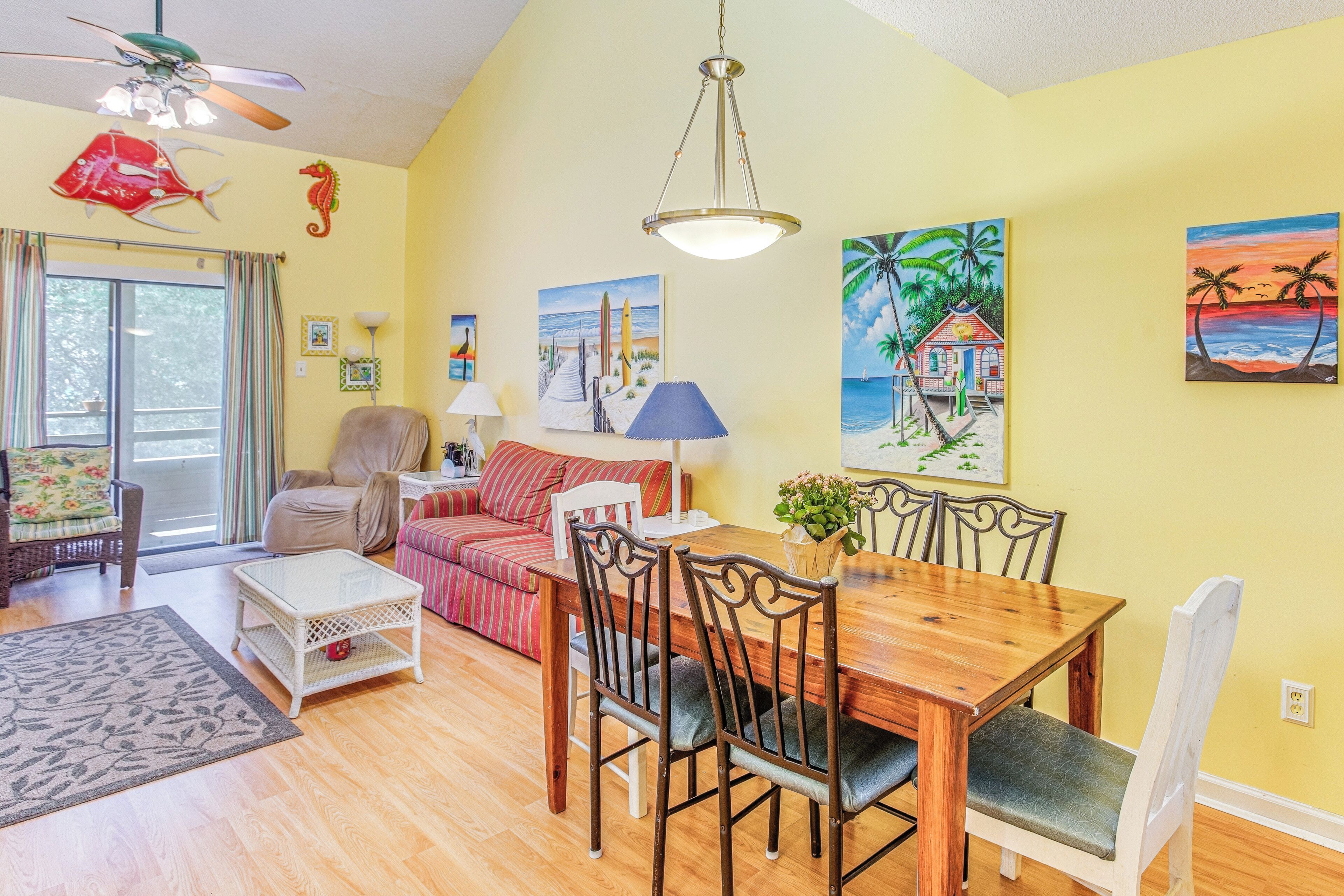 A dining area with a wooden table and chairs, a sofa, and a ceiling fan.