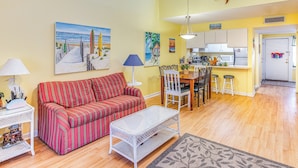 A living room with a sofa, a coffee table, and a dining area with chairs and a table. - < 1/2 Mi to the Sand! Myrtle Beach Family Condo (Myrtle Beach)