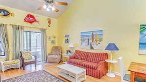 A living room with a red-striped sofa, a wicker chair, a white coffee table, and a patterned rug. - < 1/2 Mi to the Sand! Myrtle Beach Family Condo (Myrtle Beach)