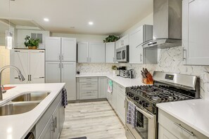 A modern kitchen with white cabinets, a stainless steel range, and a marble backsplash.