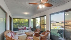 A spacious indoor area with wicker furniture, large windows, and a ceiling fan. - Fishing Dock & Fire Pit! Gulf Cove Group Getaway (Port Charlotte)
