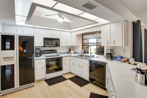A modern kitchen with white cabinets, a microwave, stove, and dishwasher.