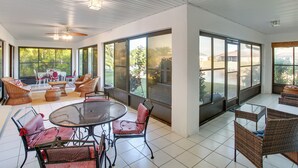 A spacious patio area with wicker furniture, a round table, and large windows offering views of the outdoors. - Fishing Dock & Fire Pit! Gulf Cove Group Getaway (Port Charlotte)