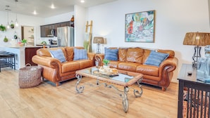 A modern living room with two leather sofas, a glass coffee table, and a dining area with a kitchen in the background. - Home w/ Private Patio 10 Mi to Rio Grande! (Las Cruces)