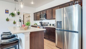A modern kitchen with stainless steel appliances, wooden cabinets, and a central island with bar stools. - Home w/ Private Patio 10 Mi to Rio Grande! (Las Cruces)