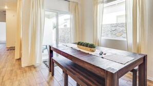 A wooden dining table with a bench, a small potted plant, and a window with curtains. - Home w/ Private Patio 10 Mi to Rio Grande! (Las Cruces)