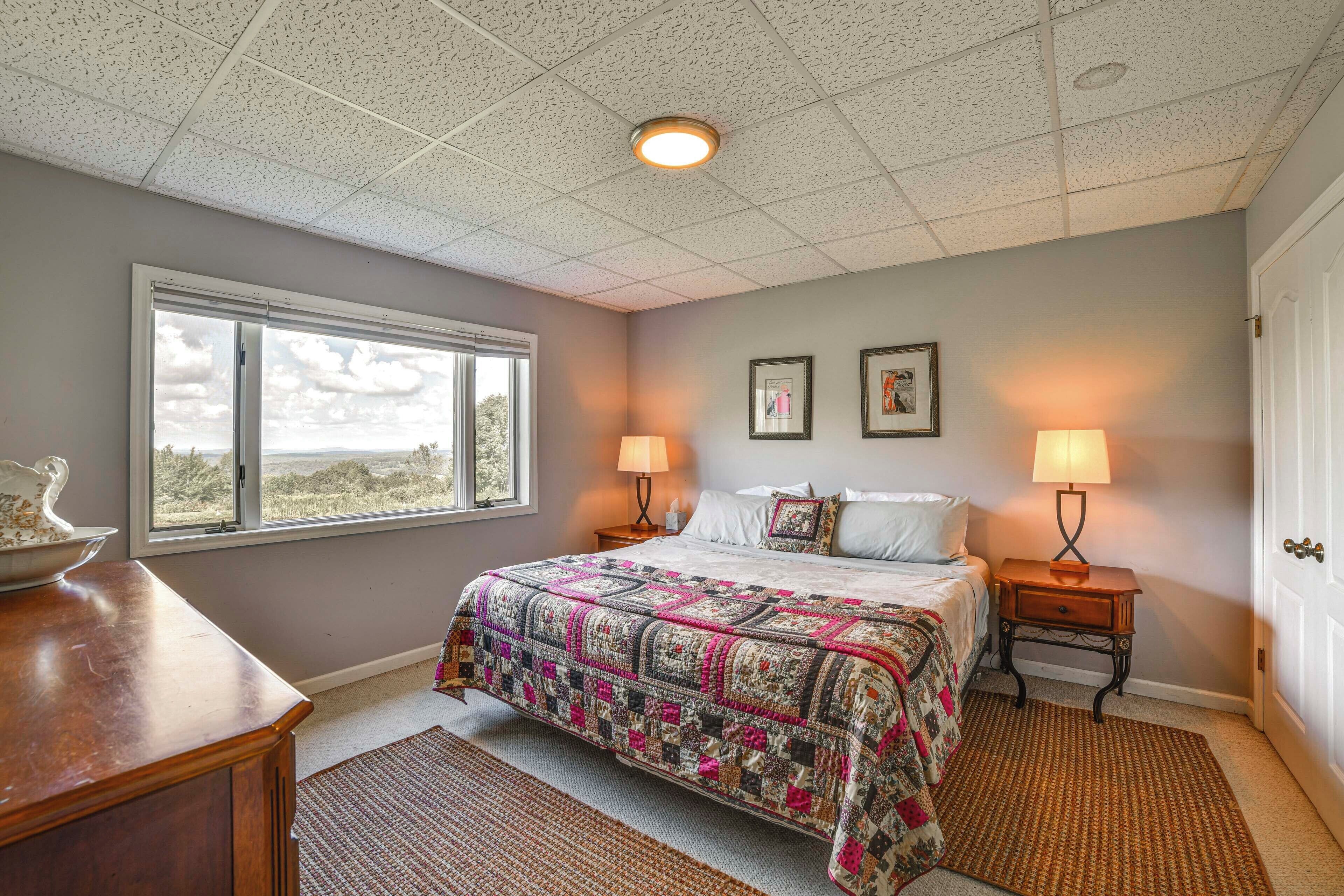 A bedroom with a large bed, two bedside lamps, a window, and a door.