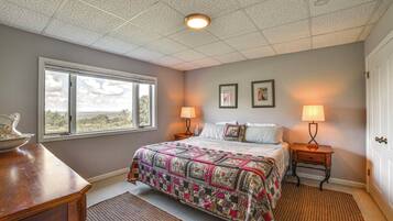 A bedroom with a large bed, two bedside lamps, a window, and a door.