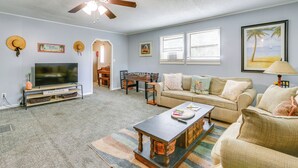 A living room with a television, sofa, coffee table, and ceiling fan.