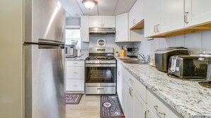 A modern kitchen with stainless steel appliances, white cabinets, and a granite countertop.