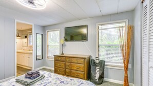 A bedroom with a bed, dresser, mirror, and windows.