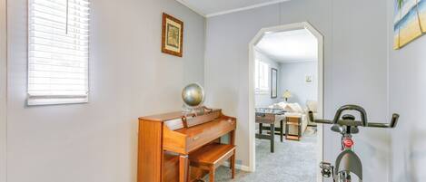 A room with a wooden desk, a globe, a bicycle, and a painting of a beach.