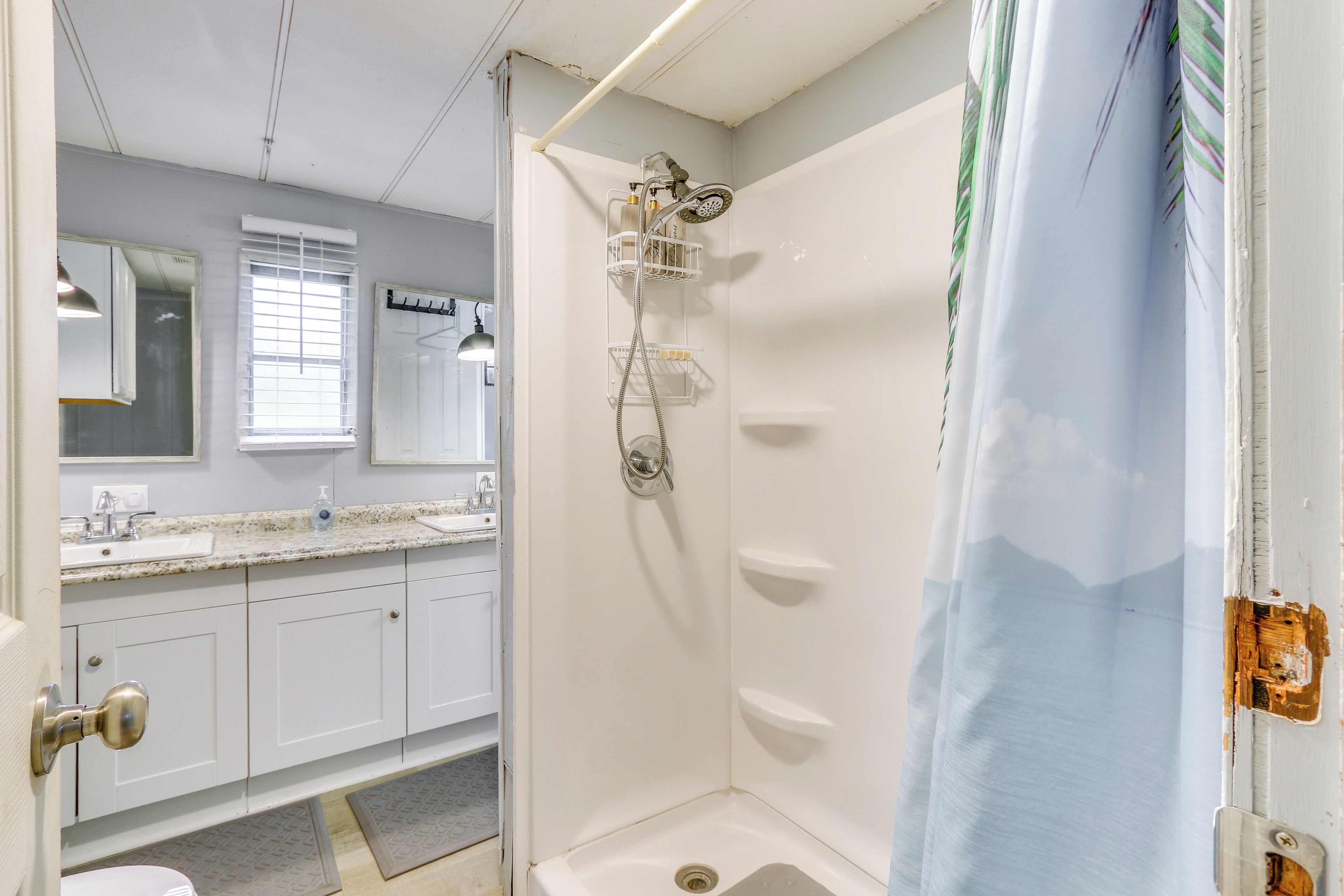 A bathroom with a shower, a sink, and a mirror.