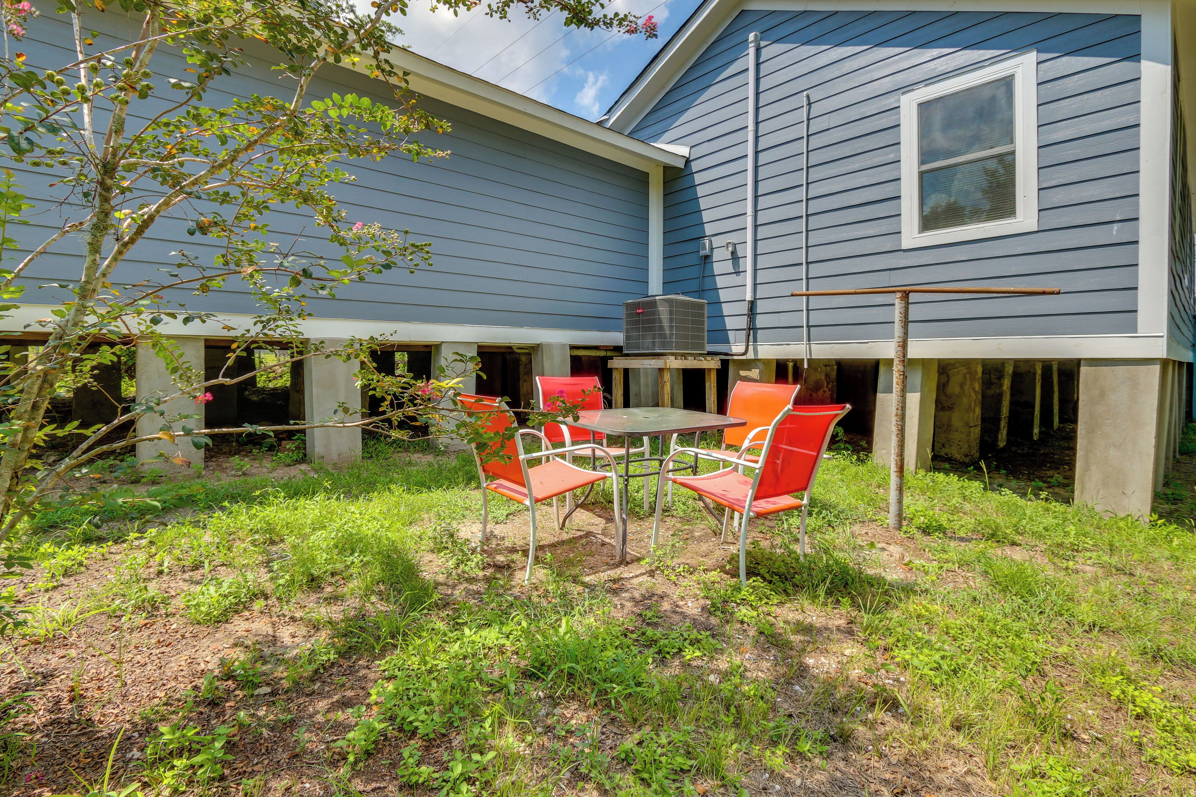 A backyard with a table and chairs, a tree, and a house with blue siding.