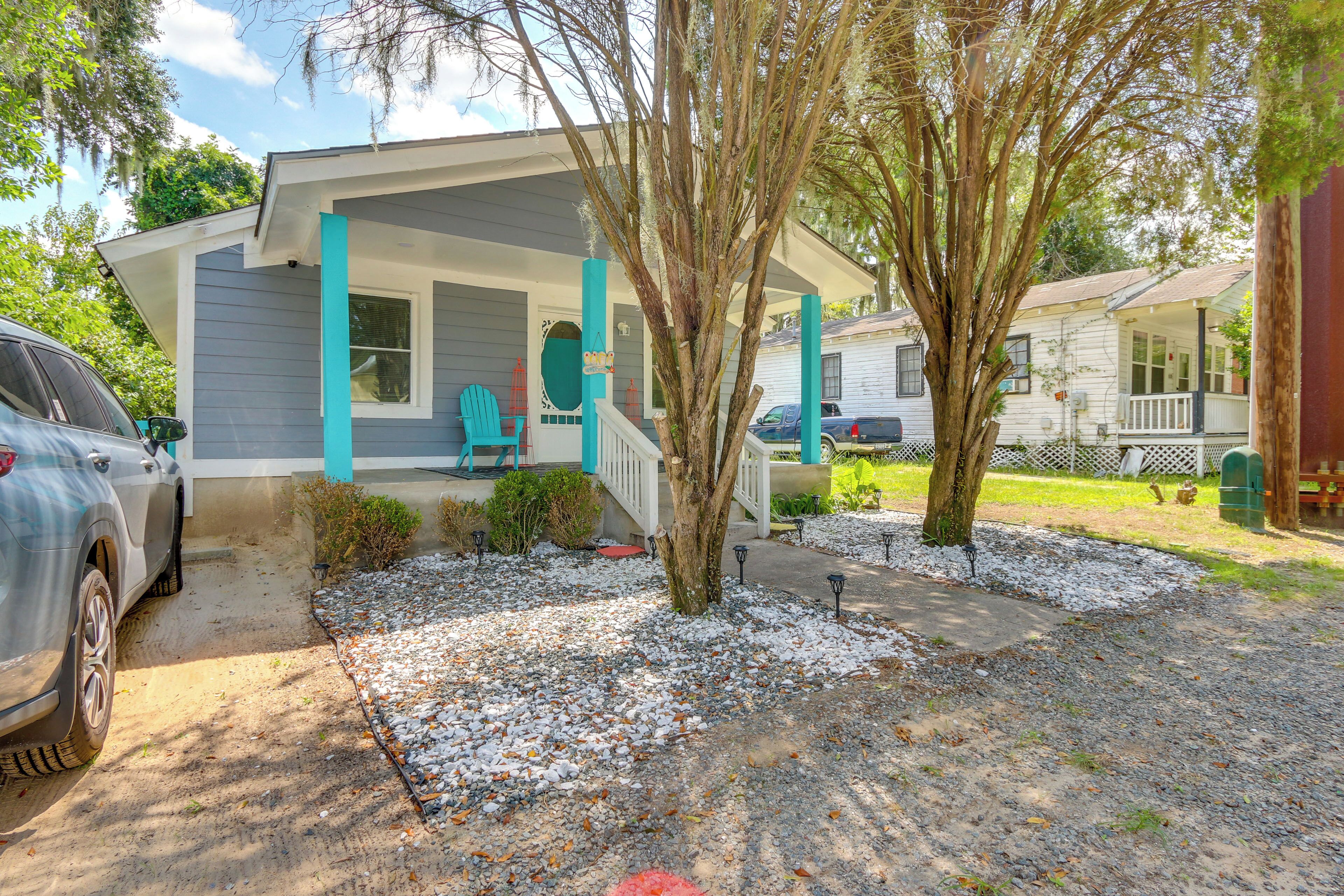 A two-story house with a porch, a car parked in the driveway, and a tree in the front yard.