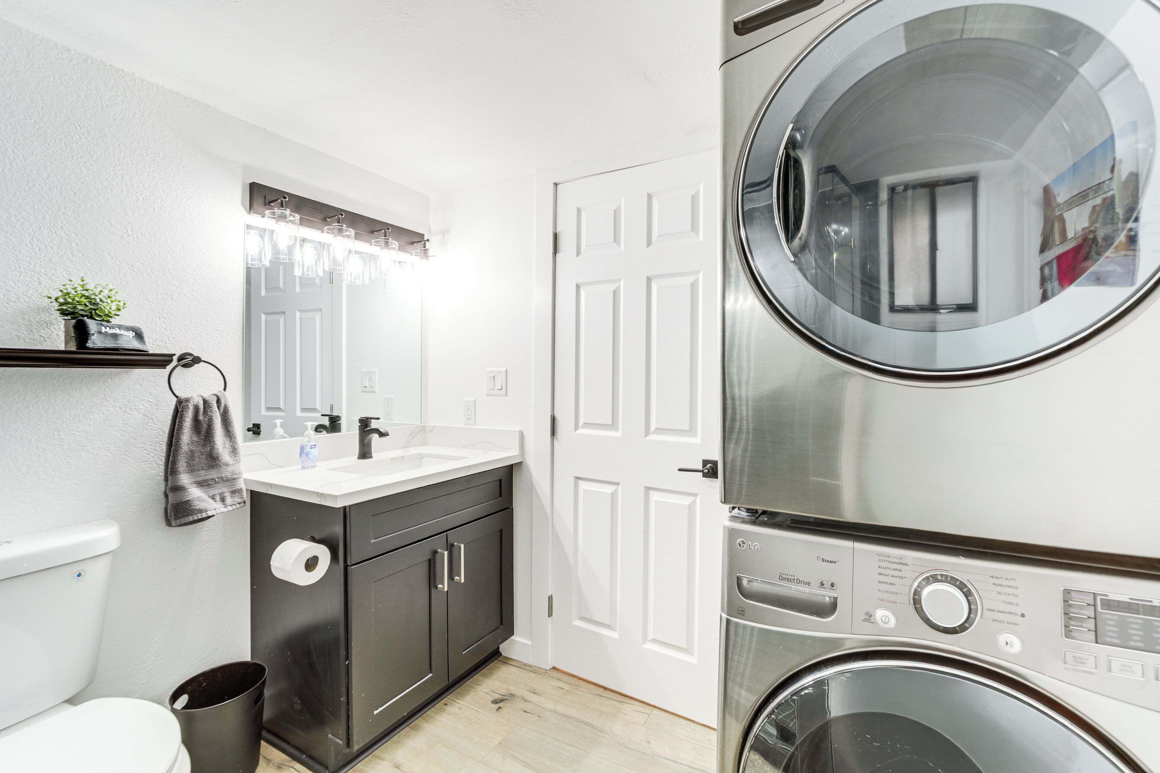A compact laundry room with a washing machine, a sink, and a toilet.