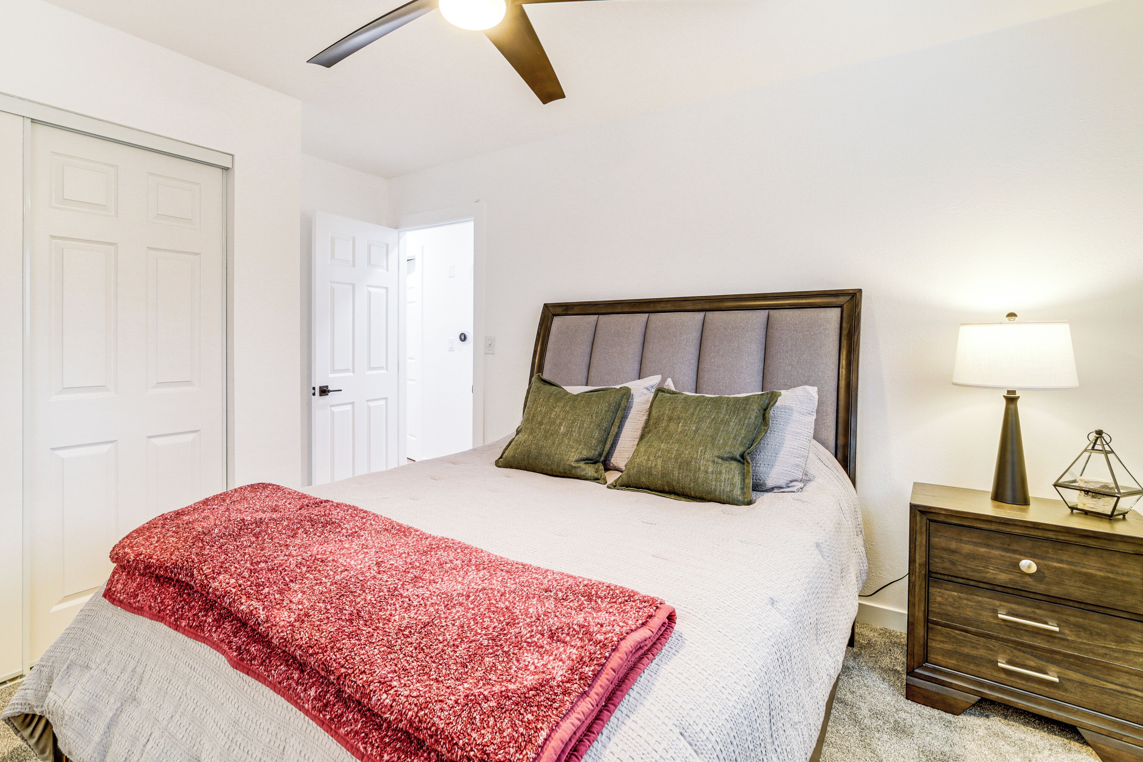 A bedroom with a bed, a nightstand, a lamp, and a ceiling fan.