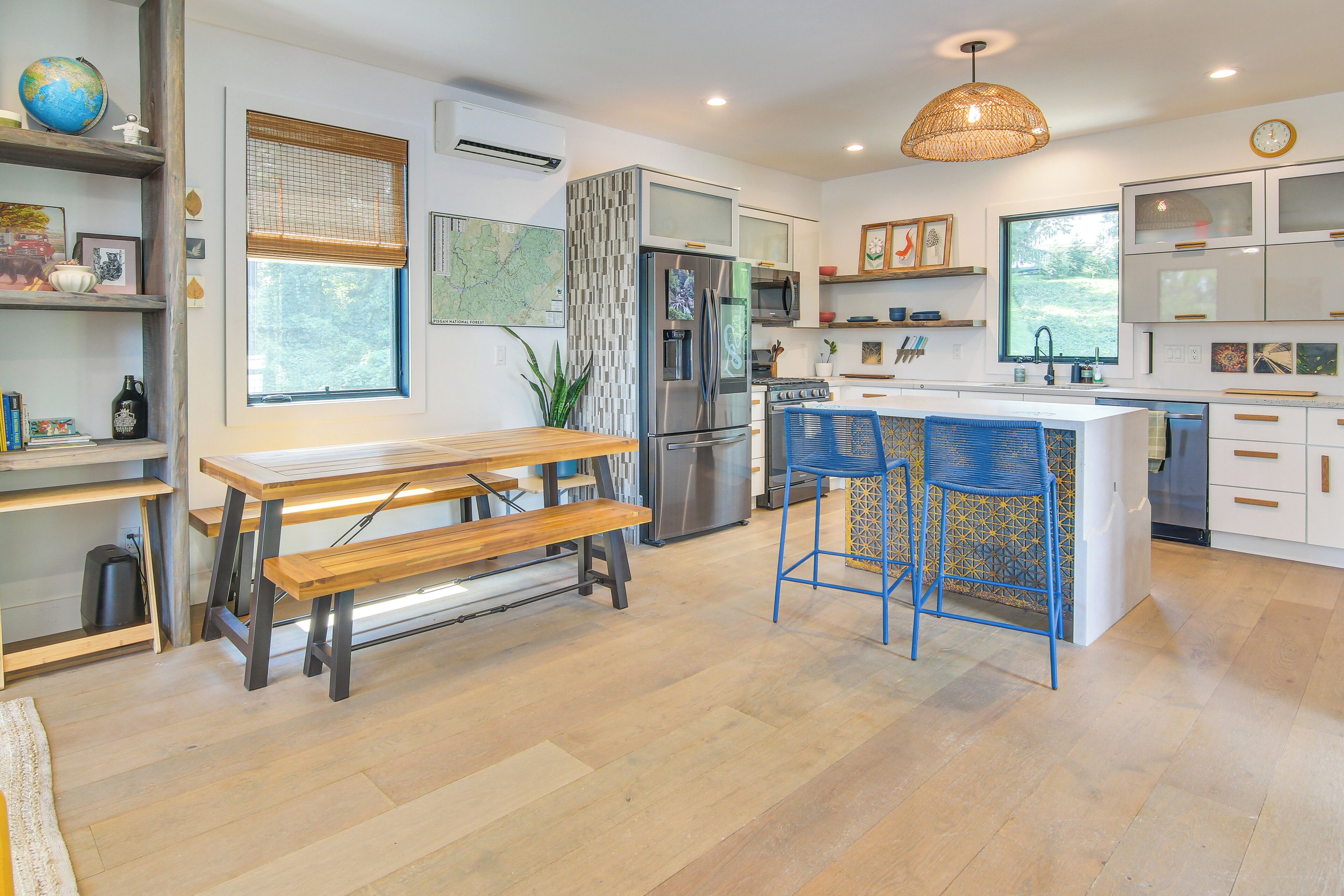 Una cucina moderna con isola centrale, elettrodomestici in acciaio inossidabile e zona pranzo con tavolo e panche in legno.