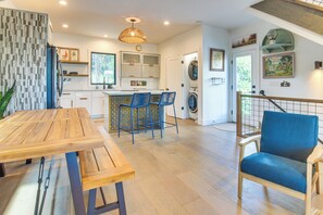 Una cocina moderna con una mesa de madera, sillas azules y una lavadora.
