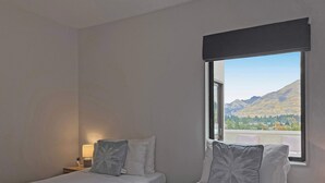 A hotel room with two beds, a nightstand with a lamp, and a window offering a mountain view. - Kiely Lane Lodge, Family-Friendly Queenstown Stay (Queenstown)