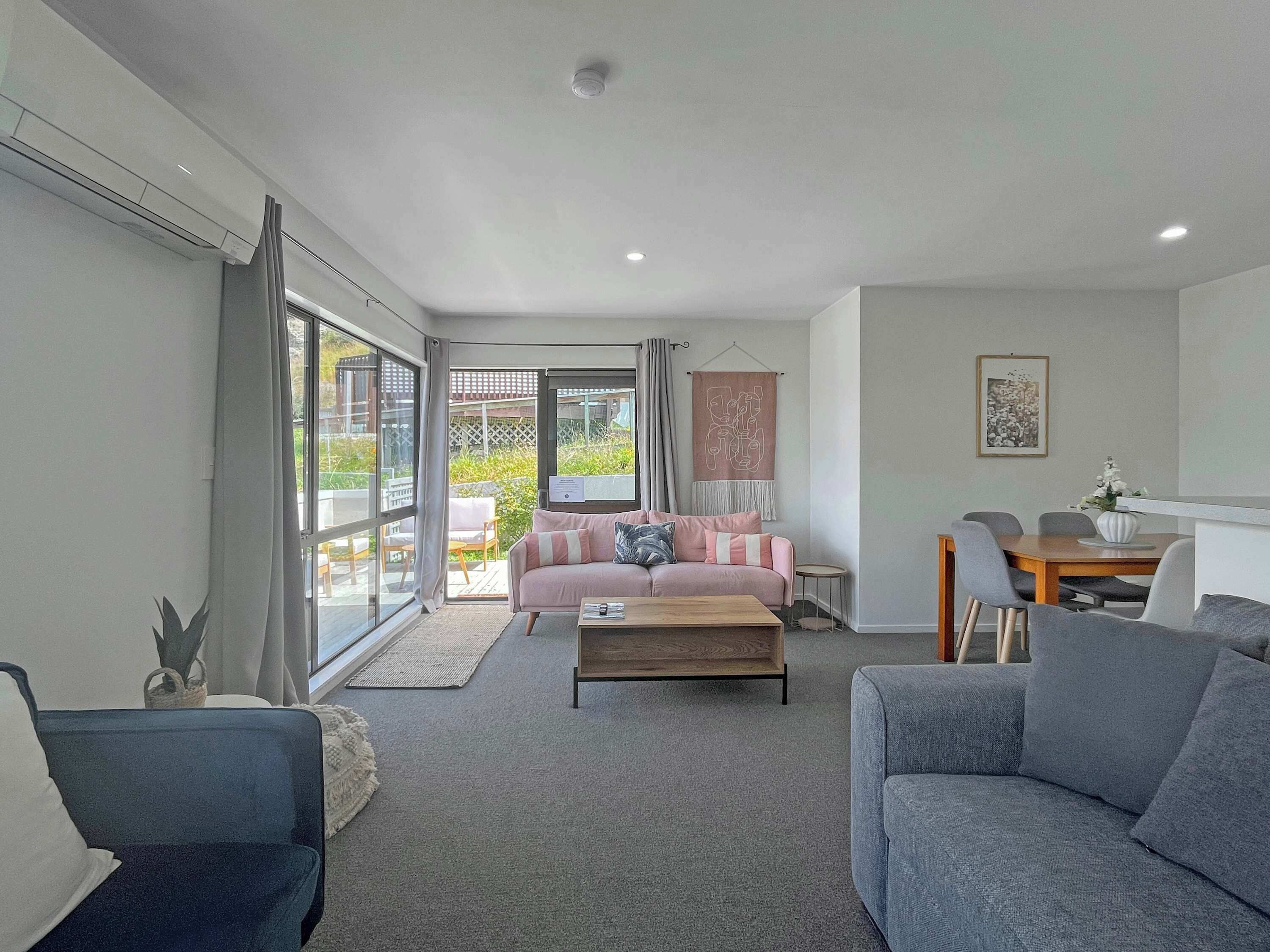 A modern living room with a sofa, a coffee table, and a dining area with chairs and a table.