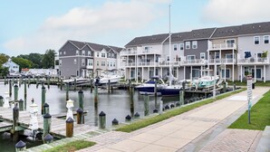 A marina with docked boats, a waterfront row of townhouses, and a paved walkway. - Walk to Dtwn! Waterfront 3BR Cambridge Townhome (Cambridge)