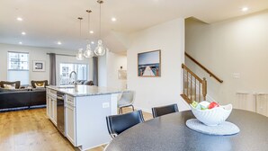 A modern kitchen with a central island, dining area with a round table, and a staircase leading to an upper level. - Walk to Dtwn! Waterfront 3BR Cambridge Townhome (Cambridge)
