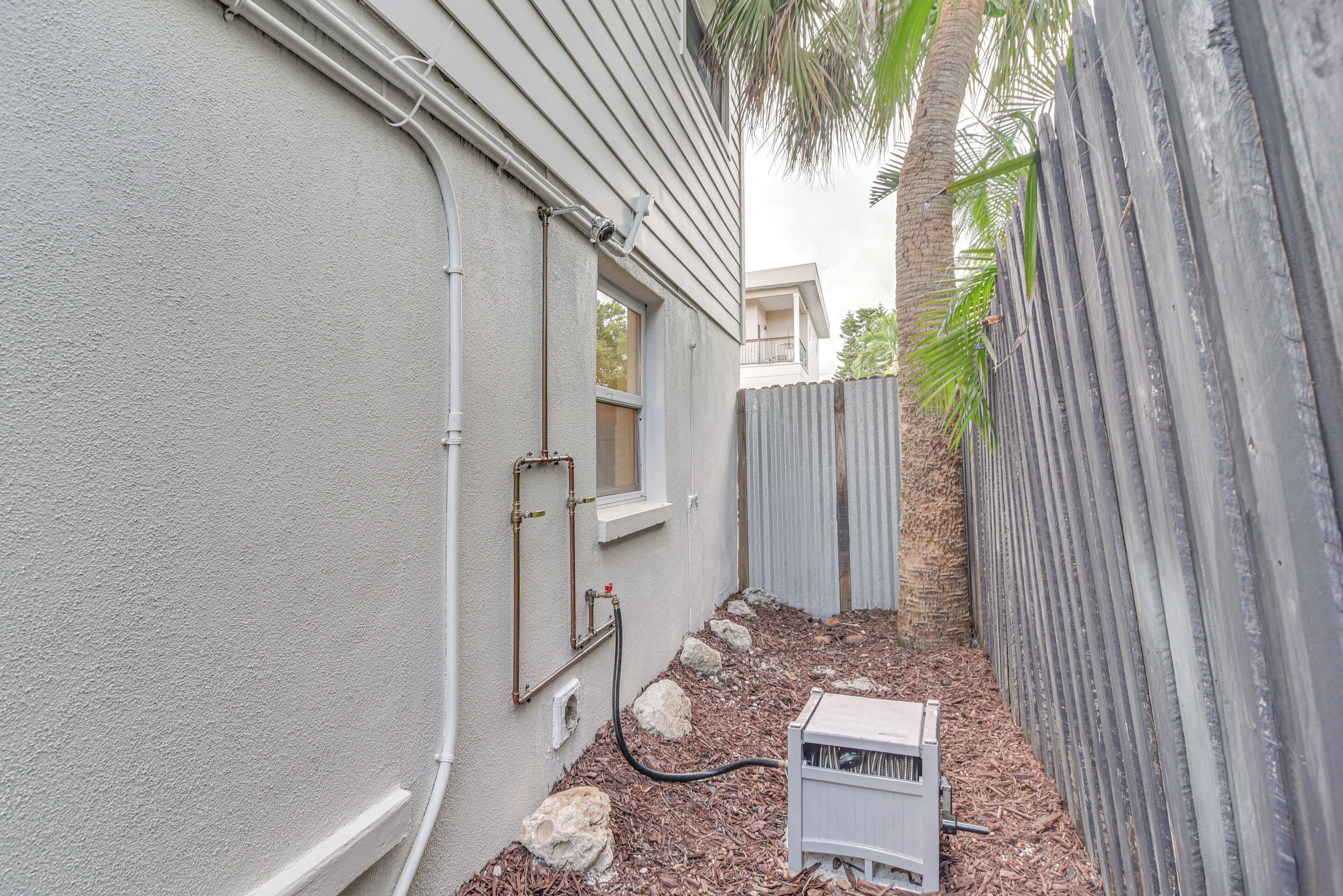 A narrow outdoor area with a white exterior wall, a window, and a white utility box.