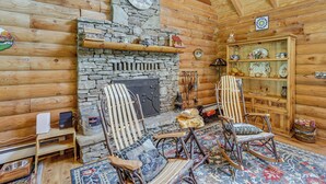 L’intérieur d’une cabane en rondins, avec une cheminée en pierre, des meubles en bois et une décoration rustique.
