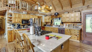 Une cuisine spacieuse dotée de meubles en bois, d’un grand îlot central et d’un coin repas avec des chaises.