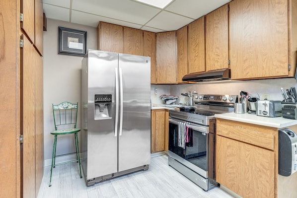 Una cocina con armarios de madera, un refrigerador de acero inoxidable, un horno empotrado y un lavamanos.