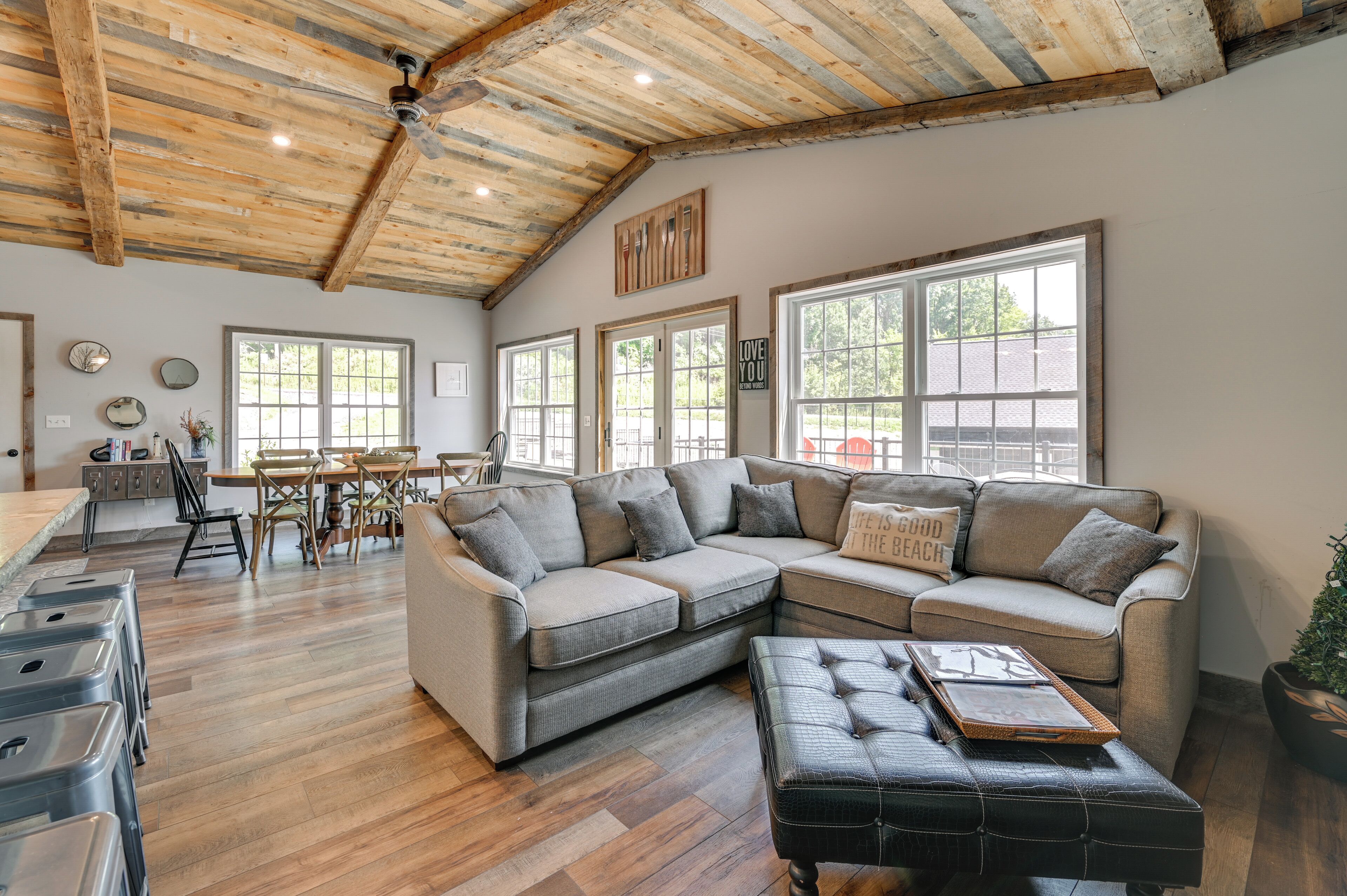 A spacious living area with a large L-shaped sectional sofa, a dining table with chairs, and a kitchen area with a countertop and cabinets.