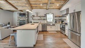 Une cuisine moderne dotée d’un îlot central, d’appareils électroménagers en acier inoxydable et d’un plafond au style rustique.