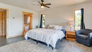 A bedroom with a bed, a chair, a nightstand, a lamp, and a ceiling fan. - Republic Retreat w/ Mountain Views & Soaking Tub (Republic)