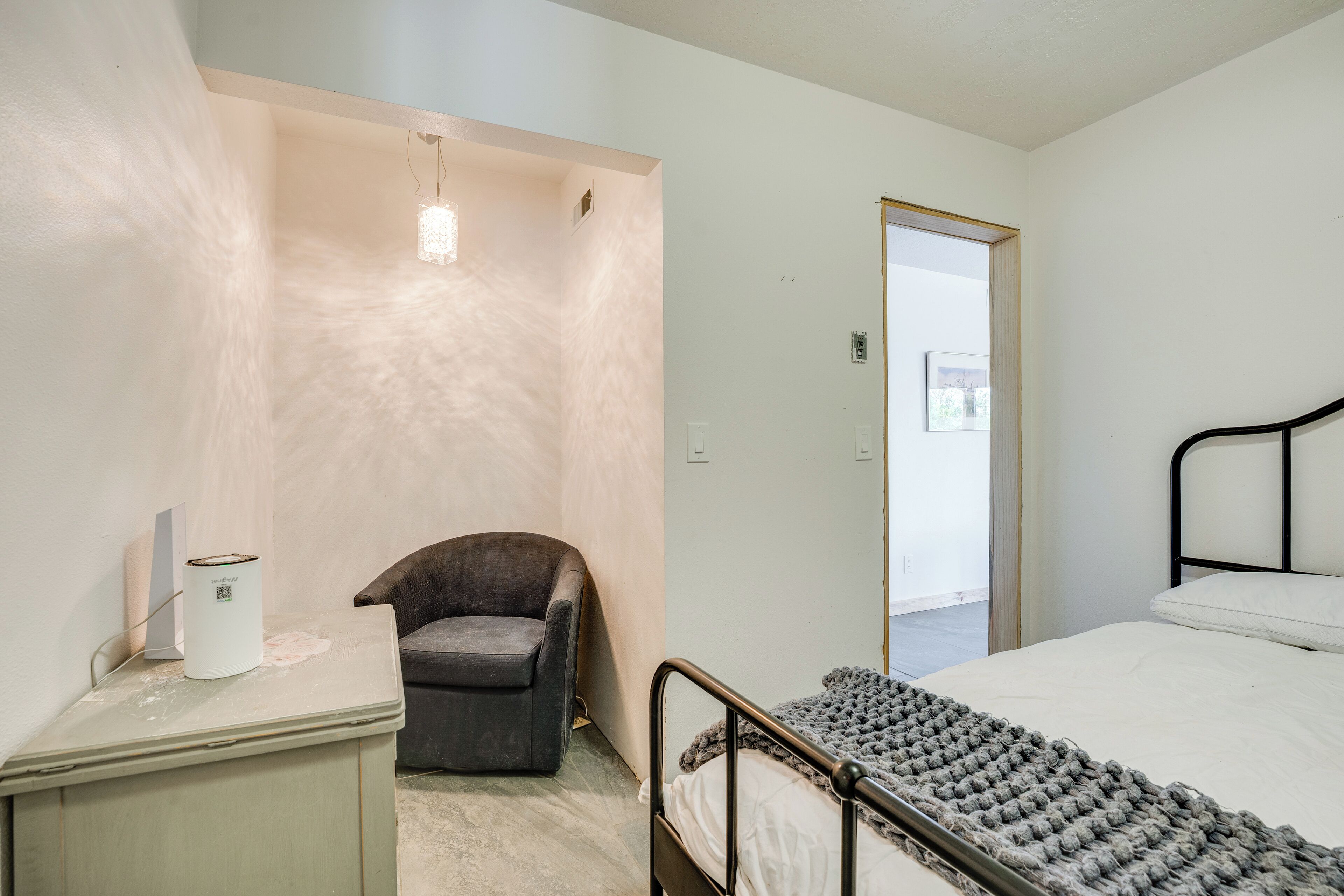 A bedroom with a bed, a chair, a desk, and a wardrobe.