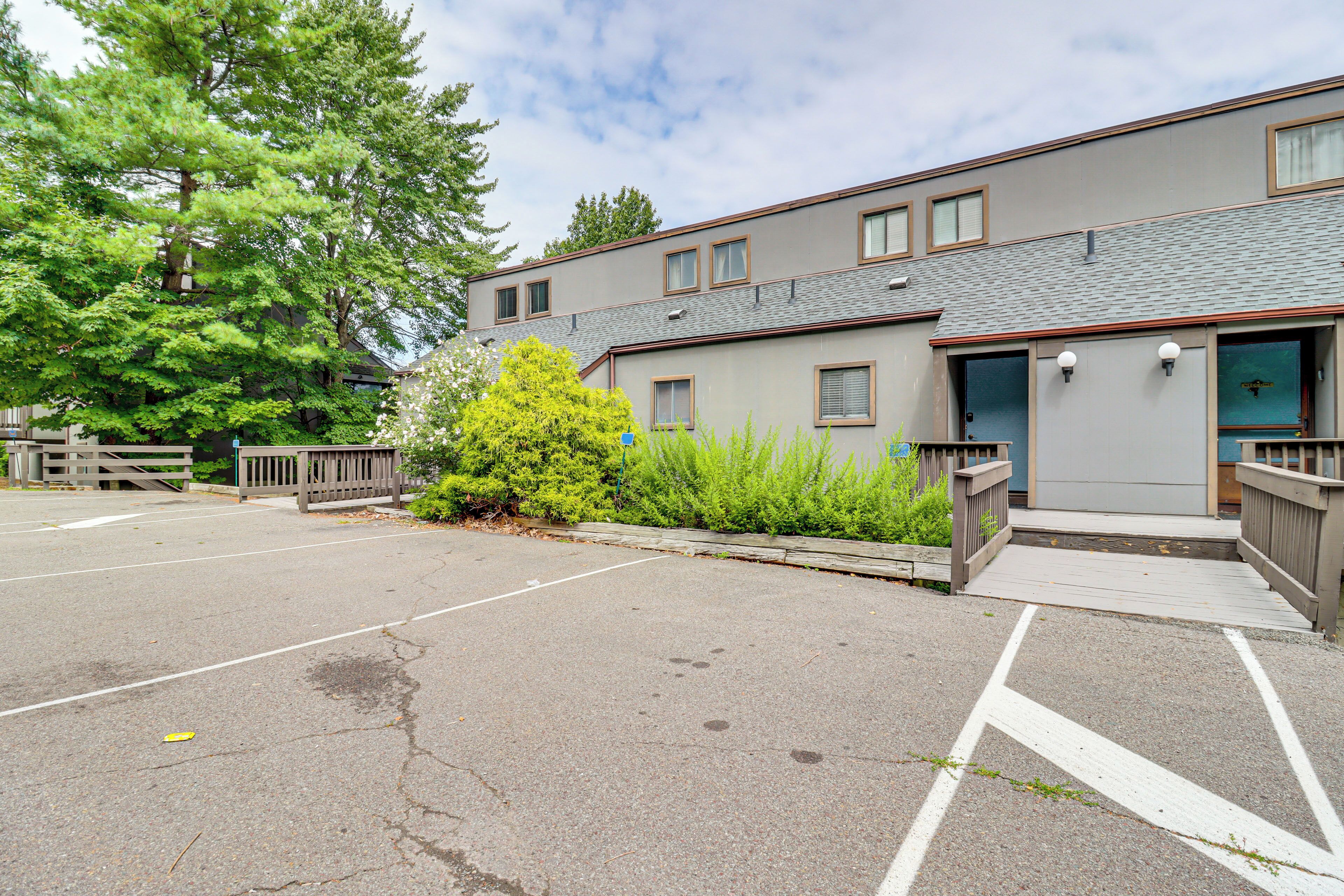 A multi-story building with a parking lot and a wooden fence.