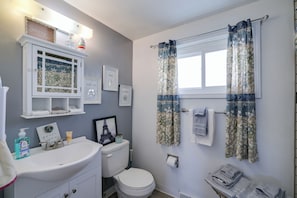 A bathroom with a white sink, toilet, and a shower curtain with floral patterns.