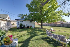 A backyard with a lawn, a tree, and a metal chair.