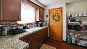 A kitchen with wooden cabinets, a granite countertop, a toaster, a sink, and a microwave. - Large Private Yard: Home 14 Mi to Niagara Falls! (Tonawanda)
