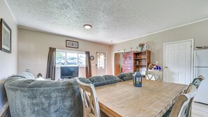 Un coin repas avec une table en bois, des chaises rembourrées, un téléviseur et une bibliothèque.