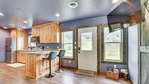 Una cocina moderna con armarios de madera, una isla central con taburetes de bar, un refrigerador y un microondas.