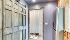 Un pasillo con puertas de madera, un refrigerador y suelo de baldosas.