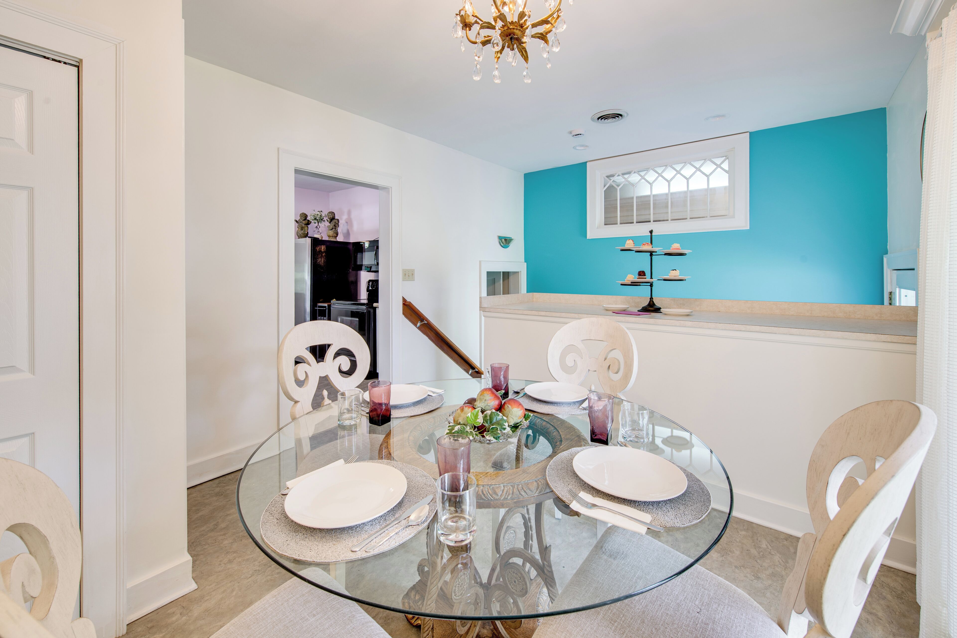 Un coin repas avec une table en verre, des chaises blanches et un mur d’accent bleu.