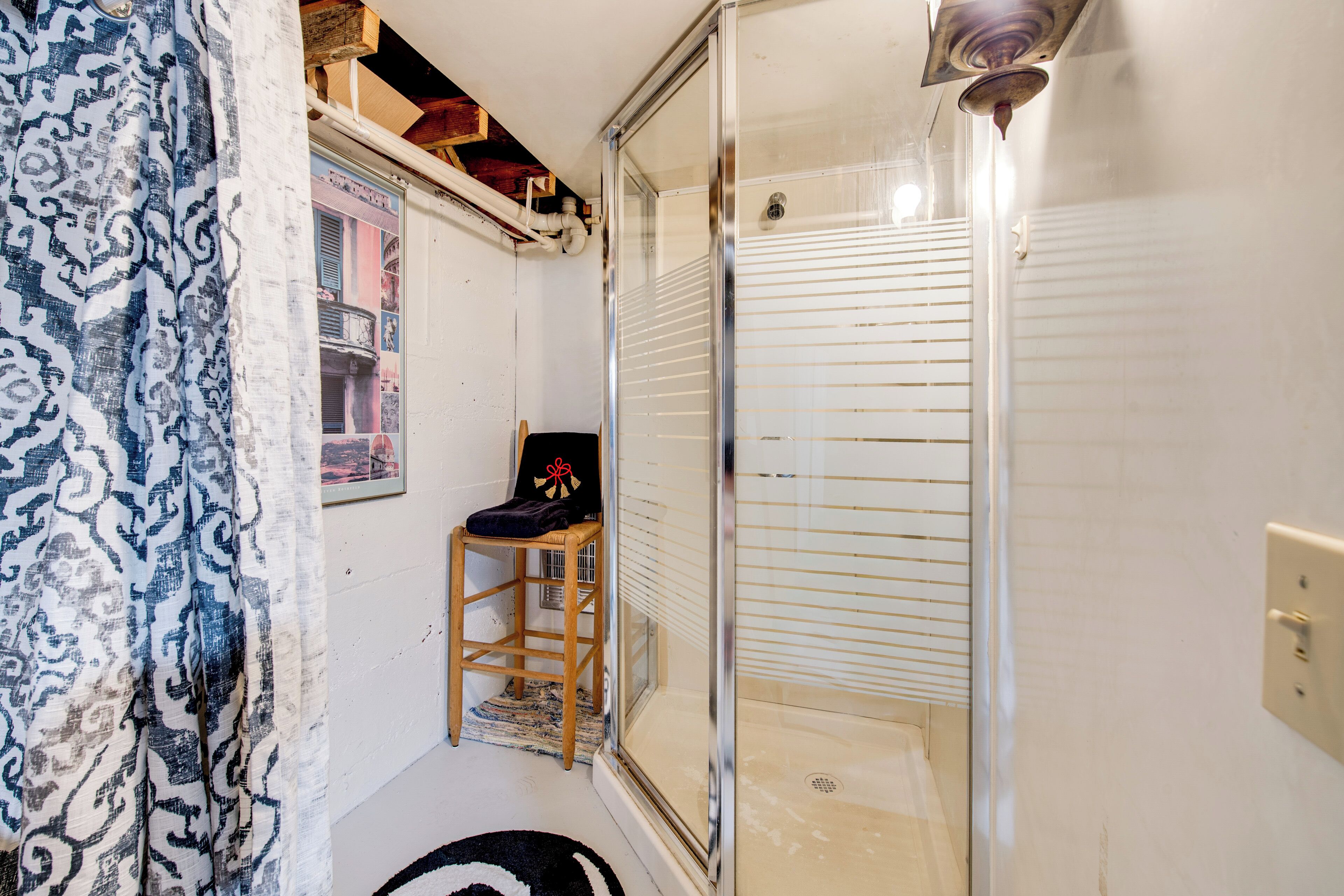 Ein Badezimmer mit Dusche, einem Stuhl, einem Handtuch und einem Fenster mit Rollläden.