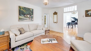 A living room with a sofa, coffee table, and a painting on the wall.