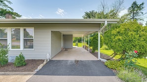 A house with a covered porch, a well-maintained lawn, and a small garden with various plants. - Near Dtwn Harrisburg: Stylish Home w/ Patio & Yard (Camp Hill)