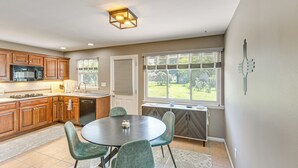 A kitchen with wooden cabinets, a microwave, and a dining area with a round table and chairs. - Near Dtwn Harrisburg: Stylish Home w/ Patio & Yard (Camp Hill)