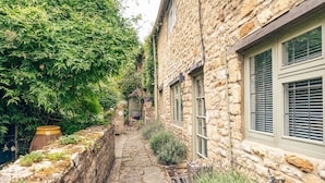 A stone building with a narrow stone pathway leading to a gate labeled "Cottage Court." - Beautifully presented dog friendly - College Cottage (Burford)