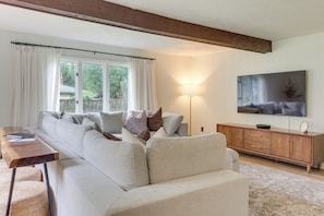 A living room with a sofa, a wooden coffee table, a TV on a wooden cabinet, and a lamp.