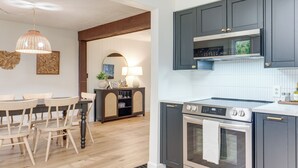 Een moderne keuken met donkere kastjes, een ingebouwde oven en een eetgedeelte met houten stoelen.